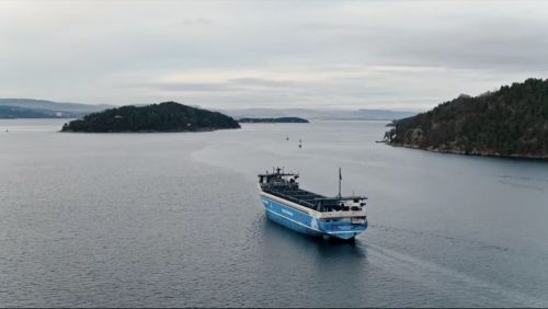 The Yara Birkeland, with fjords in the background.