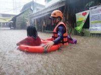 The Philippine Coast Guard helps evacuate a girl in Cagayan de Oro City. A rescue worker walks with a girl who has a life preserver around her through water up to the girl's chest.