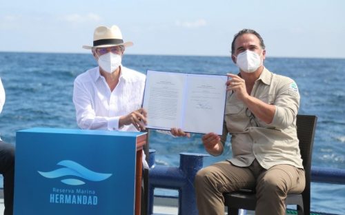 Ecuador President Guillermo Lasso and Ecuador's environment minister, Gustavo Manrique, hold up the signed document creating the Hermandad Marine Reserve