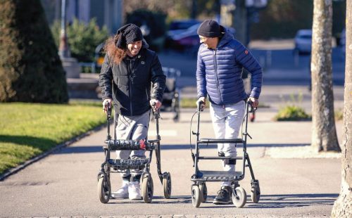Patients with spinal cord injuries walking with walkers in Lausanne.