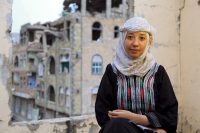 Olla al Sakkaf, a 27-year-old youth activist who works for peace in Yemen, stands in front of bombed out buildings in Yemen.