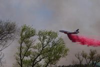 A Very Large Air Tanker (VLAT) makes a drop on a ridge west of Las Vegas New Mexico. Retardant was used to create a secondary fire containment line between the town and the advancing wildfire.