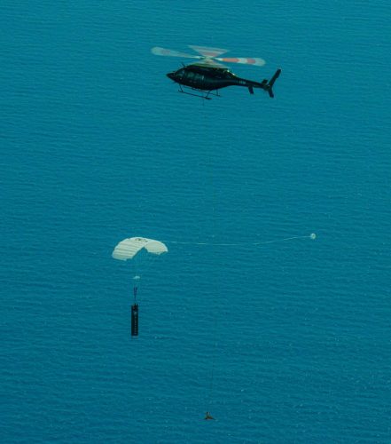 Picture of a helicopter grabbing a falling booster rocket from a test run by Rocket Lab in 2020.