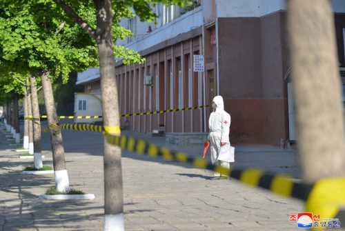 A person in a hazmat suit stands alone inside an area marked off with yellow caution tape in Pyongyang, North Korea during a Covid-19 lockdown.