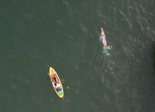 An aerial shot of Ms. Liivand on her record-breaking swim, wearing her monofin. A kayak accompanies her.