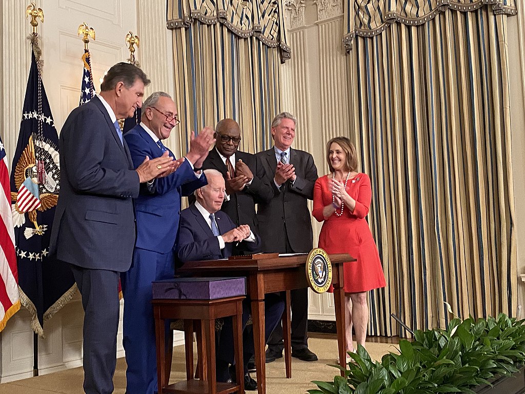 President Biden signs the Inflation Reduction Act into law on August 16, 2022. He is surrounded by prominent figures instrumental in the passage of the bill, including Senators Chuck Schumer and Joe Manchin.