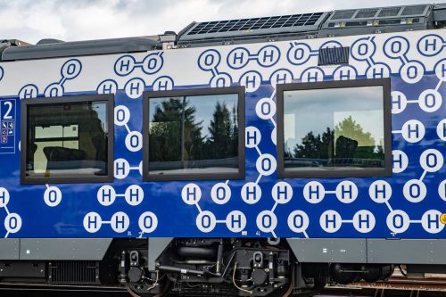 The sides of the new trains are covered with diagrams of hydrogen and oxygen molecules, along with water molecules. The image shows the blue and white side of the train with these diagrams.
