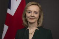 Official photo of Liz Truss – Prime Minister-designate of the United Kingdom and Leader of the Conservative Party - in front of the flag.