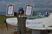 Mack Rutherford, standing in front of his microlight aircraft holds up certificates for his two Guinness World Records.