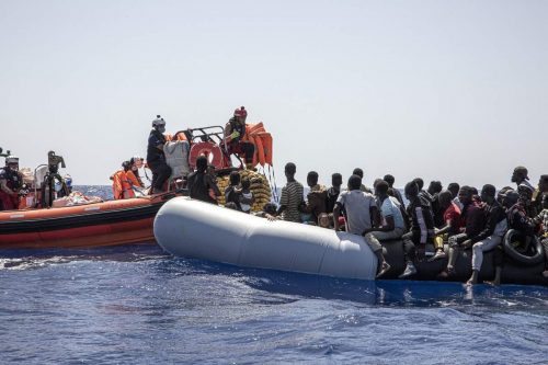 Boat workers from the SOS Mediterranee group work to rescue migrants on an overcrowded inflatable boat in August 2022.