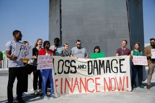 Protesters at COP27 hold up signs in support of Loss and Damage payments.