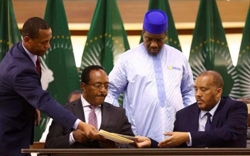 Above people representing the two sides sign the peace treaty.