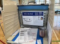 Image of a voting carrel, with a ballot on the writing surface. At the back of the carrel is a sign showing how to fill in the oval to vote on the ballot. (Source: Ryan Dickey, via Flickr.com.)