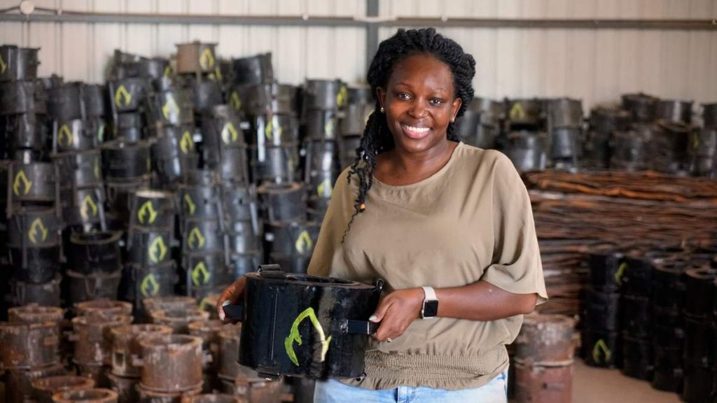 Charlot Magayi holds one of her stoves. In the background are piles of Mukuru Clean Stoves.