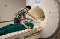 Jerry Tang, the lead scientist on the experiment, prepares a person to go into an MRI machine.