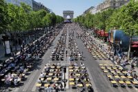 Long shot from the air of participants sitting at desks on the Champs-Elysees prepare to take part in the Big Dictation.