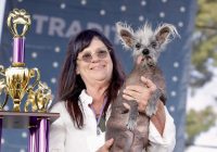 Linda Elmquist holds Scooter next to the first prize trophy for the World's Ugliest Dog.