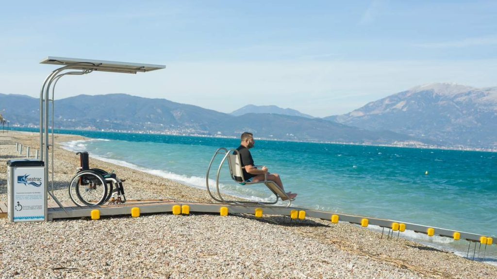 A man rides toward the sea in the chair of the Seatrac system. His wheelchair remains on the beach.
