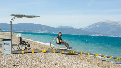 A man rides toward the sea in the chair of the Seatrac system. His wheelchair remains on the beach.