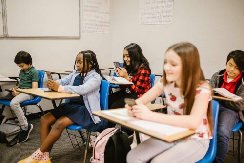 Students sitting inside the classroom while using their smartphones