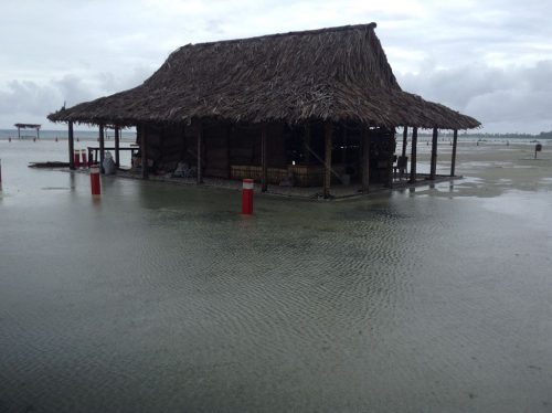 A simple building with a thatched roof surrounded by water during flooding in Funafuti, Tuvalu in 2017