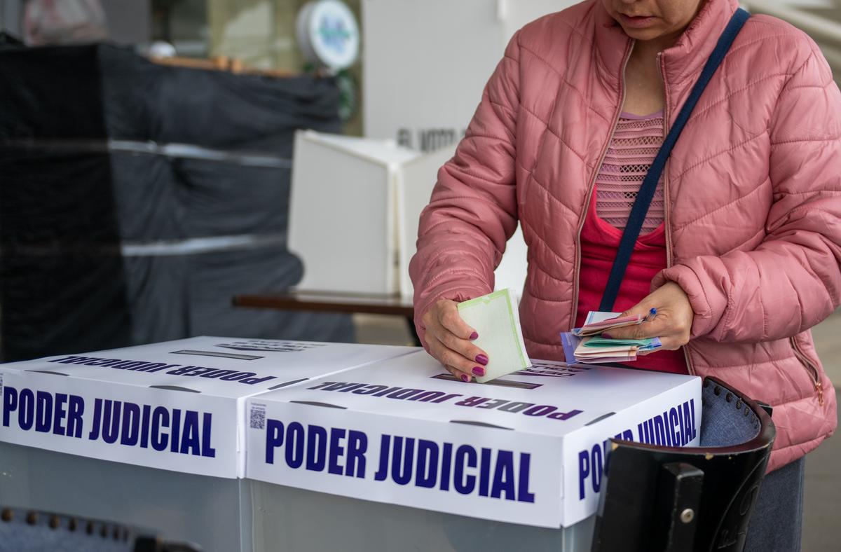 A voter puts ballots in a voting box during Mexico's national election of judges on June 1, 2025.