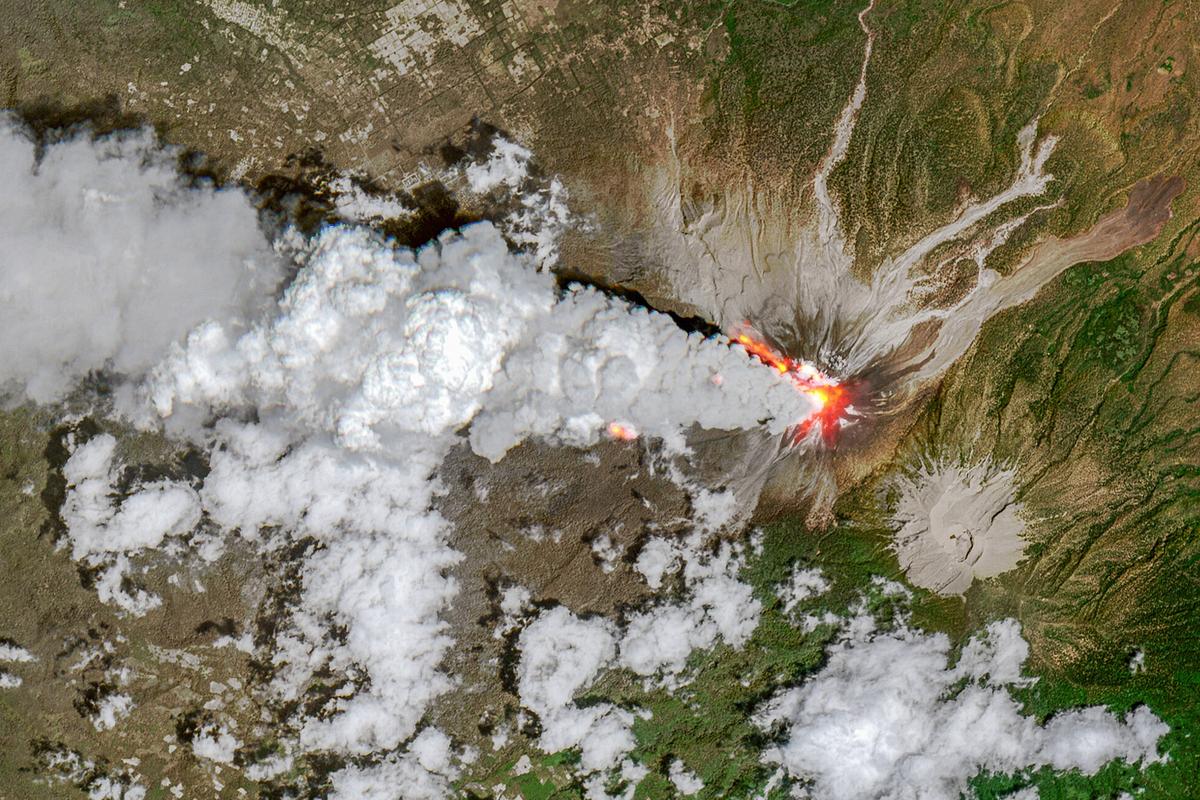 Mount Lewotobi Volcano, Flores, Indonesia - November 13th, 2024. In this aerial view, fire and smoke can be seen pouring from the volcano, while an inactive volcanic peak can be seen to the right.