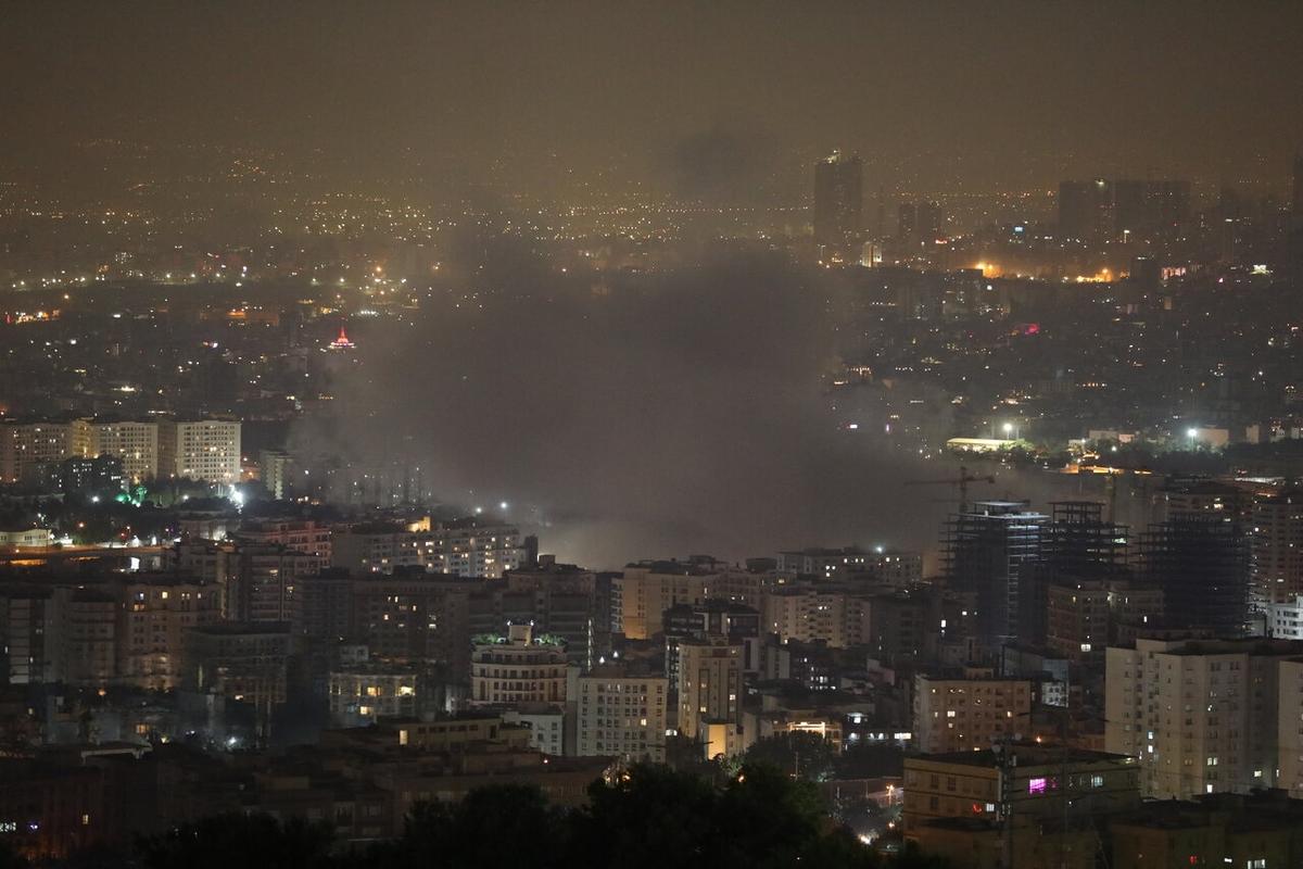 The army of Israel attacked parts of Tehran at dawn on Friday, June 13, 2025. Smoke can be seen billowing in the center of the picture, with a background a dark cityscape with lighted windows in buildings.