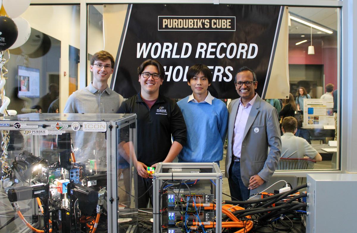 The Purdubik’s Cube robot, a high-speed robotic system that can solve a scrambled Rubik’s Cube in just 0.103 seconds, is seen with most of the team that created the robot. From left to right, Matthew Patrohay, Aden Hurd, and Junpei Ota, along with one of their professors, Milind Kulkarni.