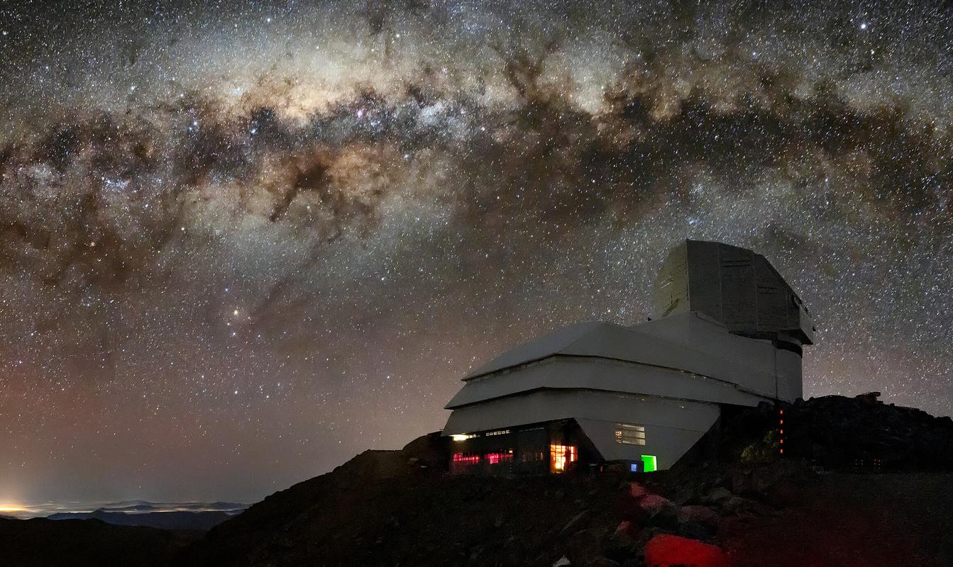 This image captures the Vera C. Rubin Observatory as well as the Milky Way. The bright halo of gas and stars on the left side of the image highlights the very center of the Milky Way galaxy.