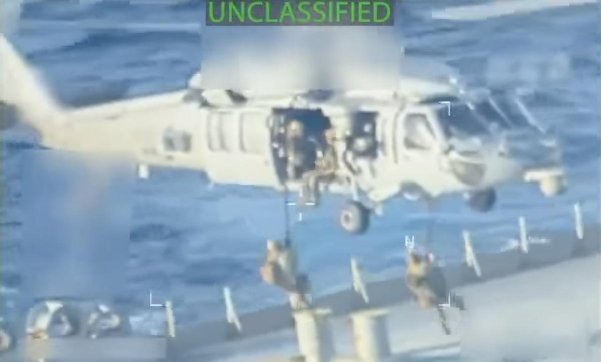 United States military personnel lowering themselves onto the oil tanker Skipper from a helicopter using ropes.