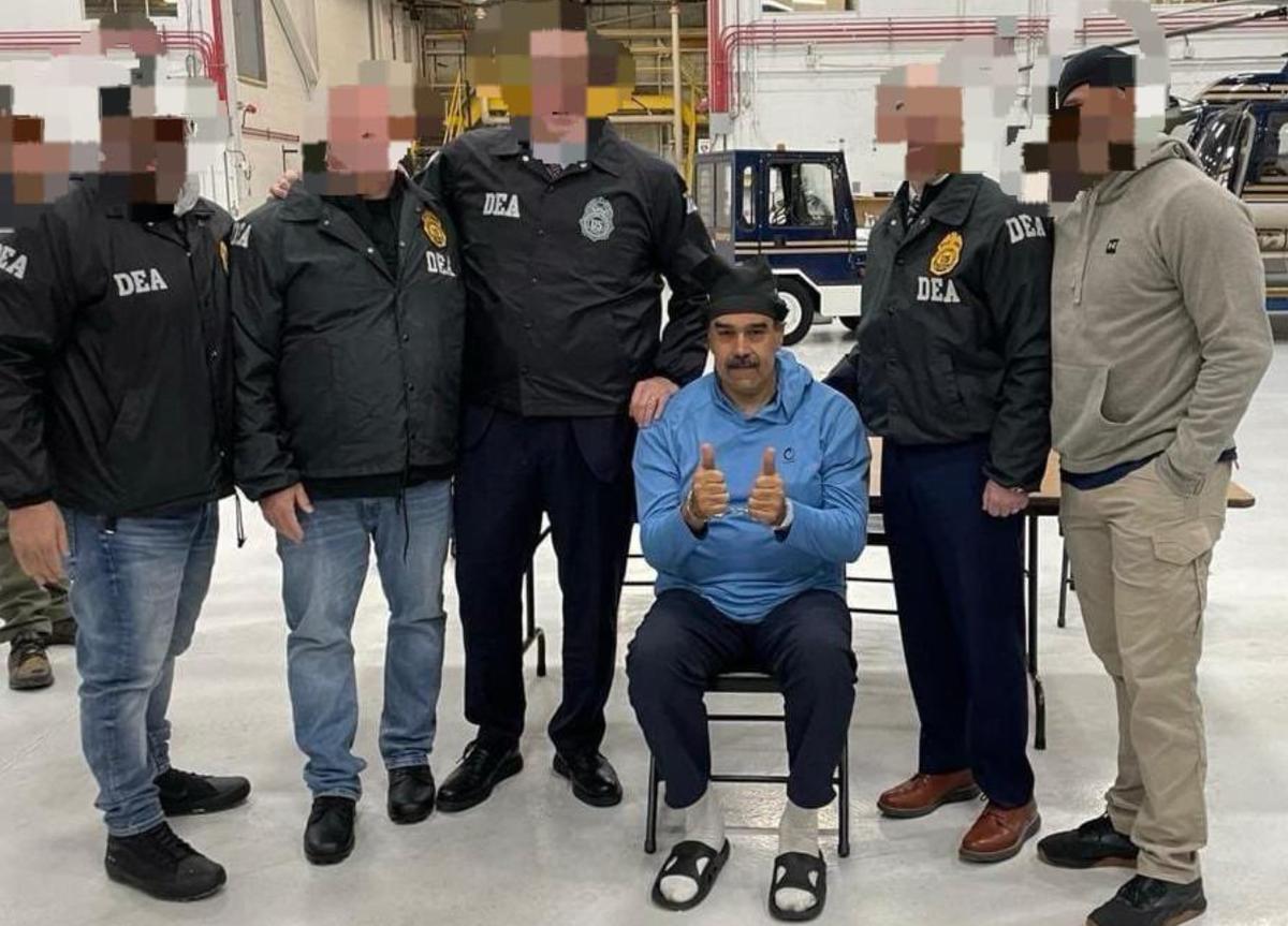 A photo released by the DEA shows captured Venezuelan leader Nicolás Maduro seated, wearing a hoodie and surrounded by five standing DEA agents after his arrival in New York under U.S. custody. The faces of all but Maduro have been blurred.
