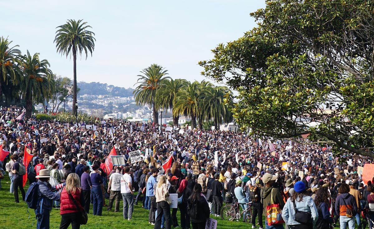 Large crowd in Mission Dolores Park for San Francisco ICE OUT protest on January 30 2026 with palm trees in the background.