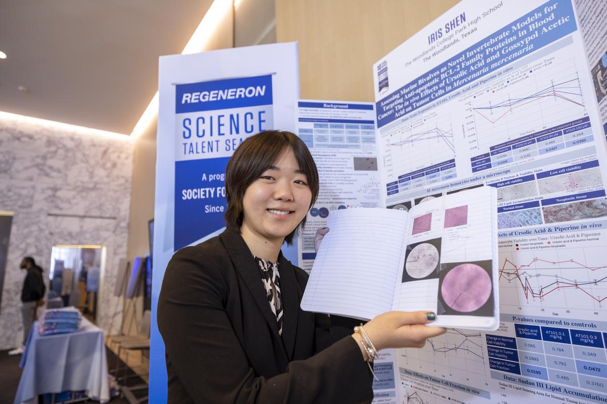 Iris Shen poses with her third place project, which investigated using clams for assessing cancer drugs. Iris holds a notebook which contains some of her research.