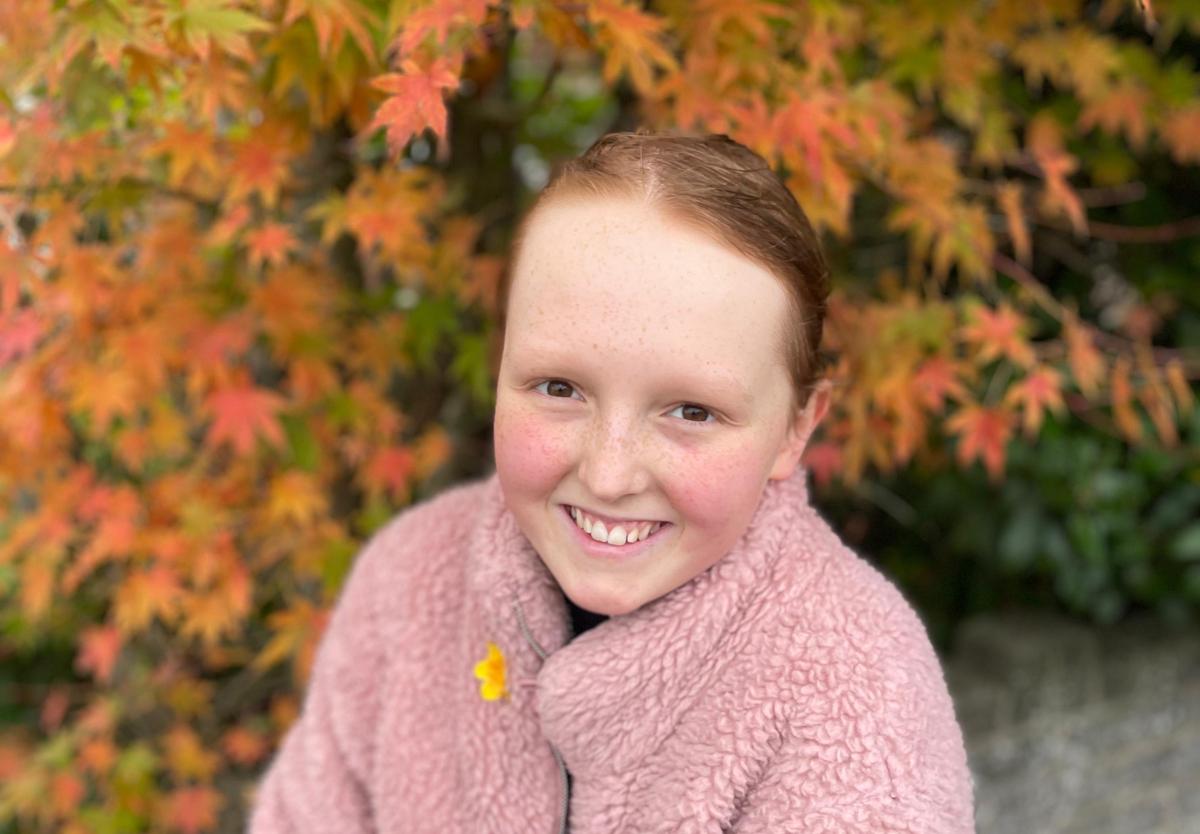 Kirsty smiles at the camera with autumn leaves in the background behind her.