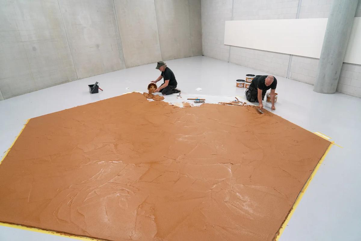 Two workers spread peanut butter to create the Peanut Butter Floor artwork.