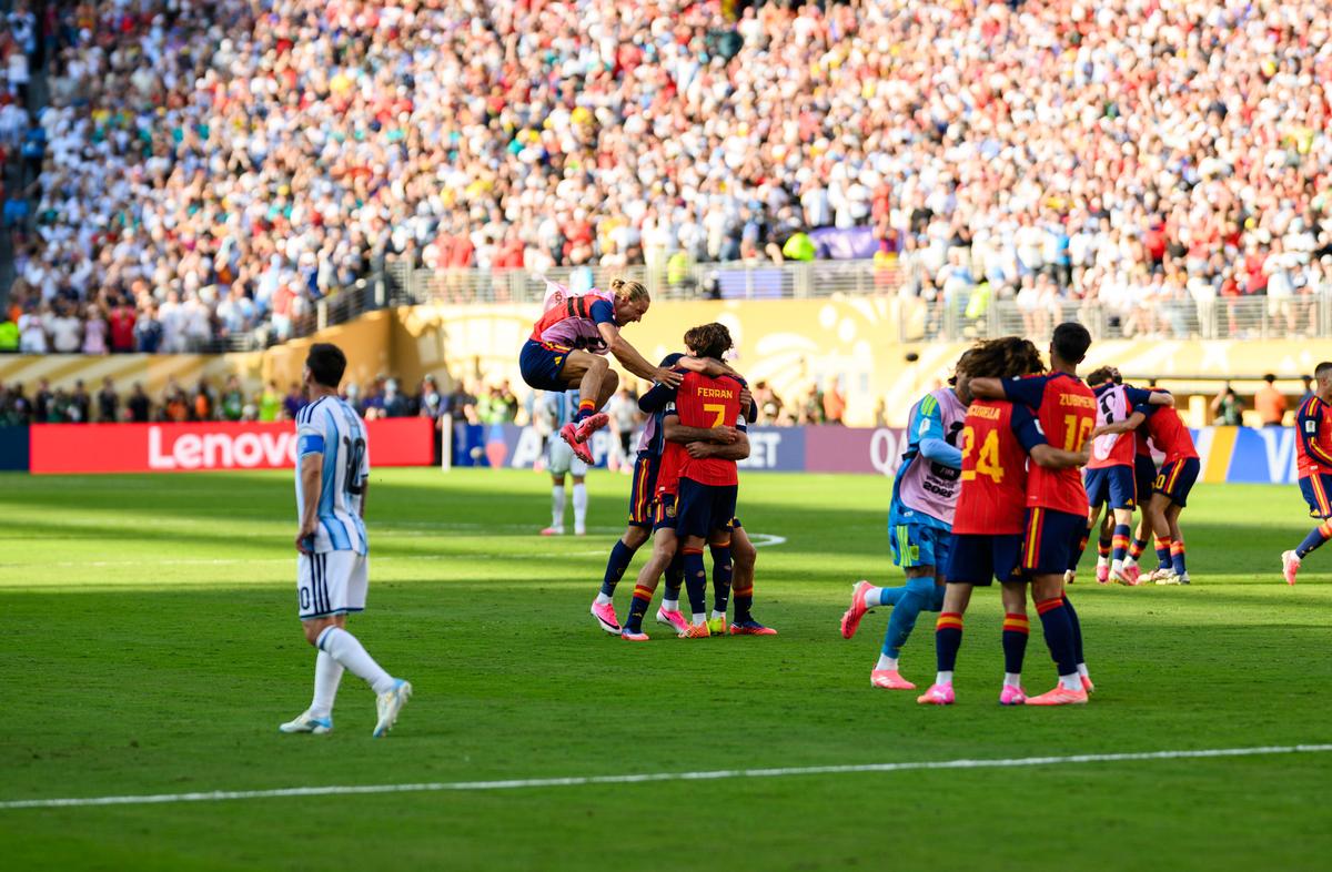 Argentina's Leo Messi is seen walking away to the left as Spanish athletes hug and celebrate their World Cup victory.
