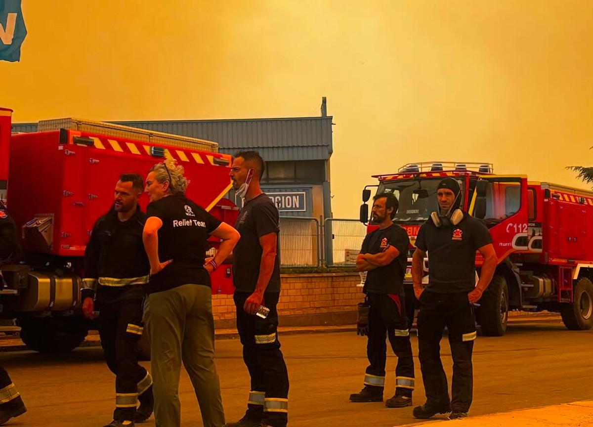 Firefighters and others seen against the orange haze of wildfire smoke in Âvila Province, Spain on July 25, 2026.
